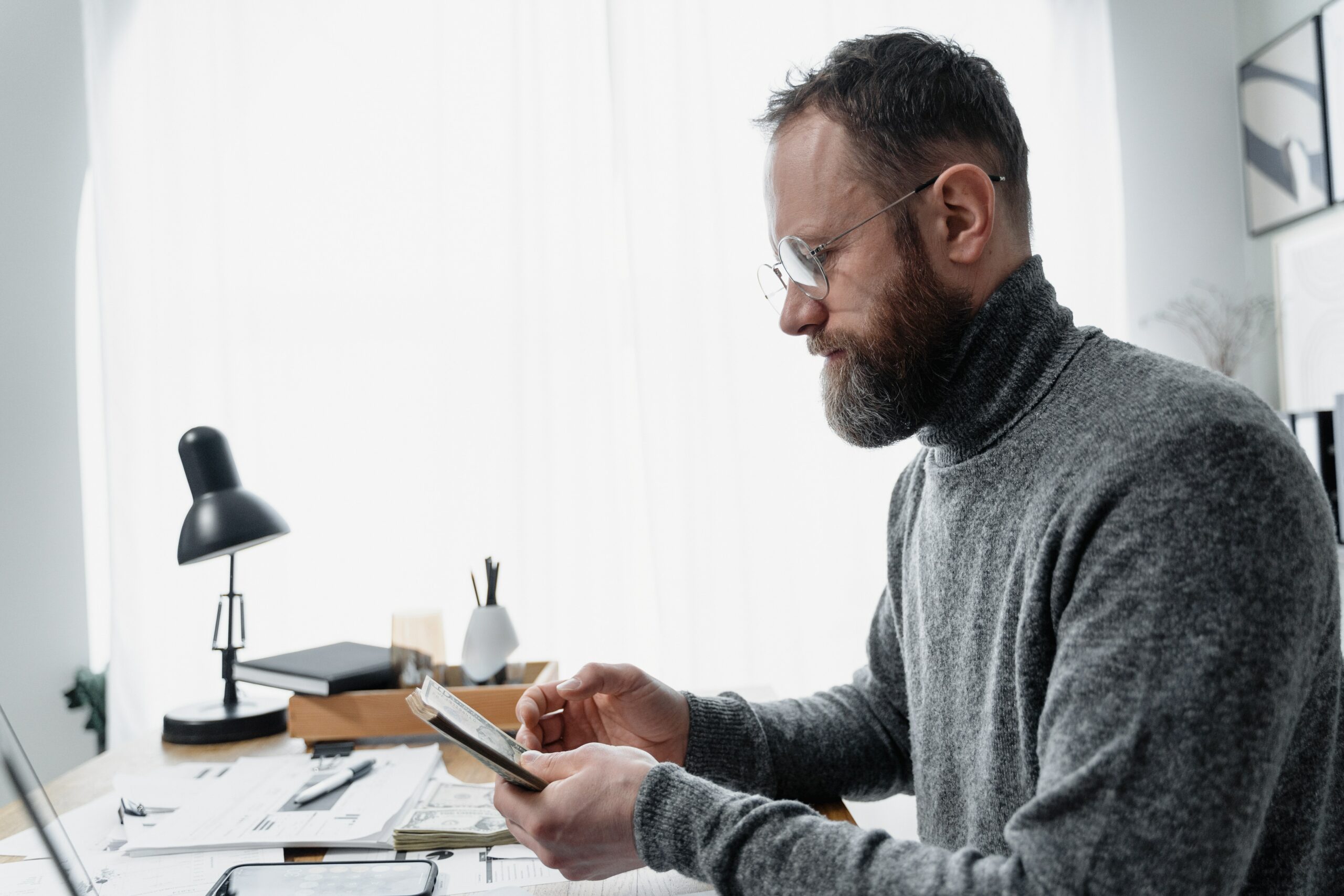 Bearded man counting money doing payroll