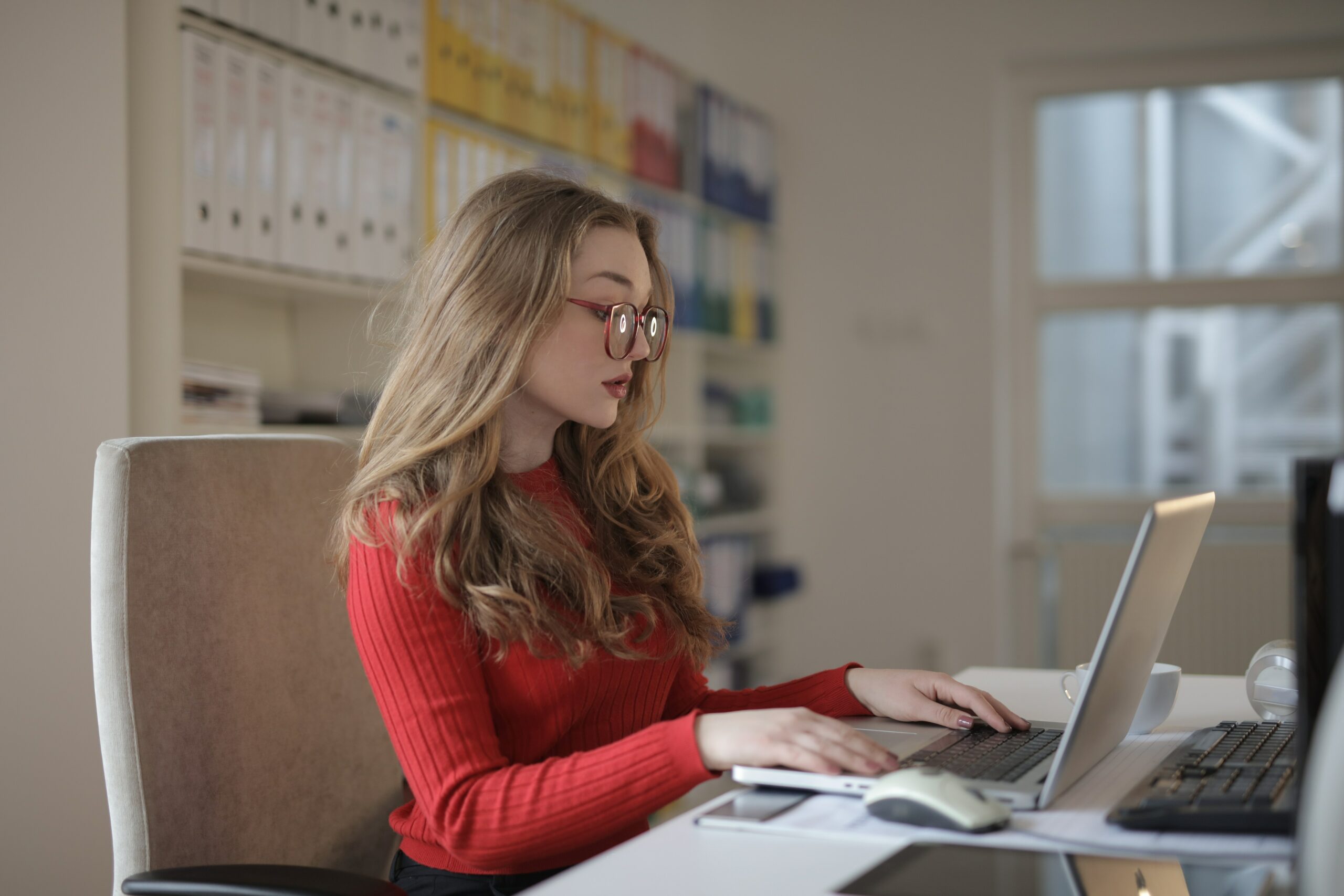 Young woman dressed in red doing finance on a laptop